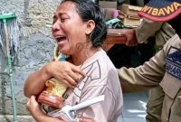 Sambil menangis, korban penggusuran di Jalan Irian Jaya, Else de Hoog keluar dari rumahnya dengan memeluk erat patung Bunda Maria/Foto : RakyatFlores.com